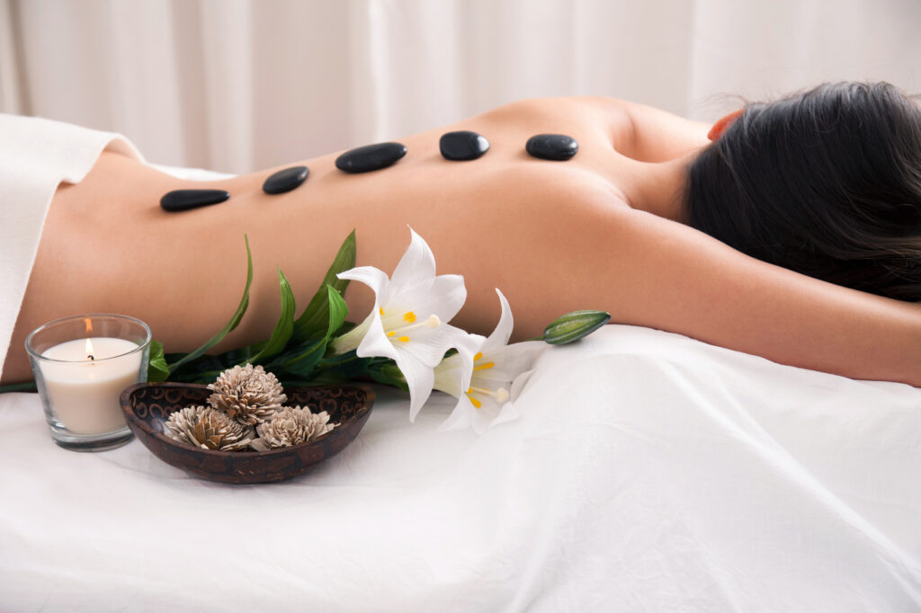 Dame liegt auf einer Massageliege während einer Hot-Stone-Massage