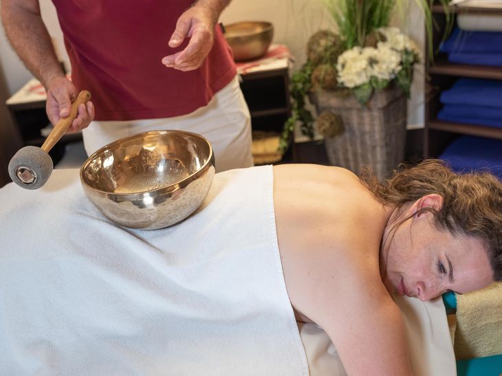 Dame liegt auf einer Massageliege während einer Klangschalenmassage